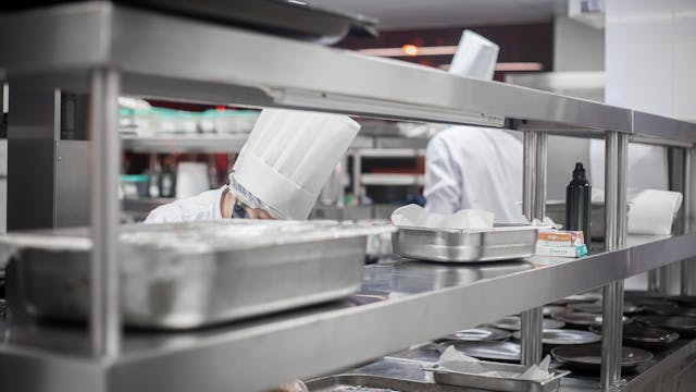 Chefs working diligently in a modern stainless steel kitchen, preparing delicious dishes.