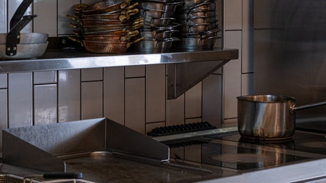 Industrial kitchen setup with stainless steel appliances, pots, and pans.