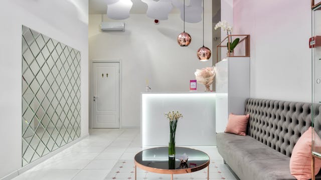 Interior design of contemporary reception hall with comfortable sofa and table for guests and stylish lamps hanging on ceiling